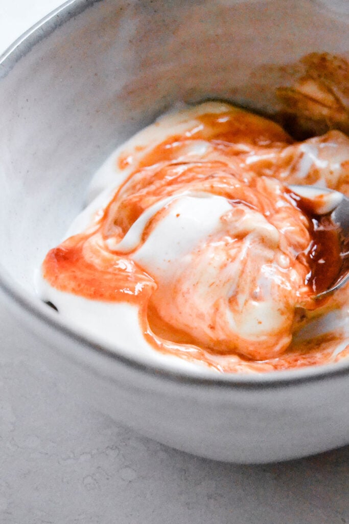 mixing the vegan spicy mayo in a small grey bowl.