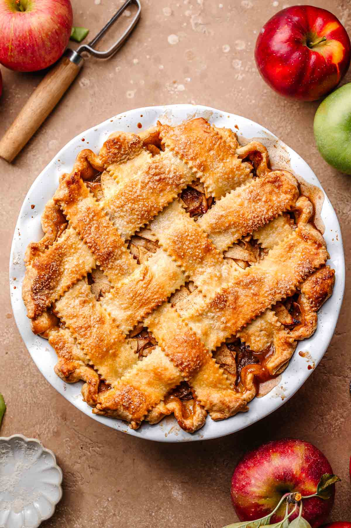 Golden brown baked vegan apple pie with a lattice crust, showing fluted edges and glistening sugar topping.