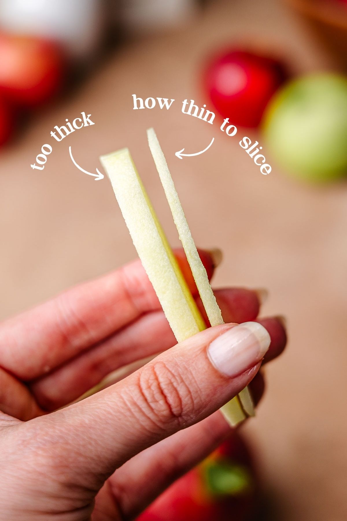 a hand holding two apple slices, one thick and one the correct thinness.