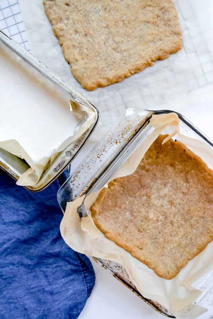 the baked cookie base in a glass square baking dish.