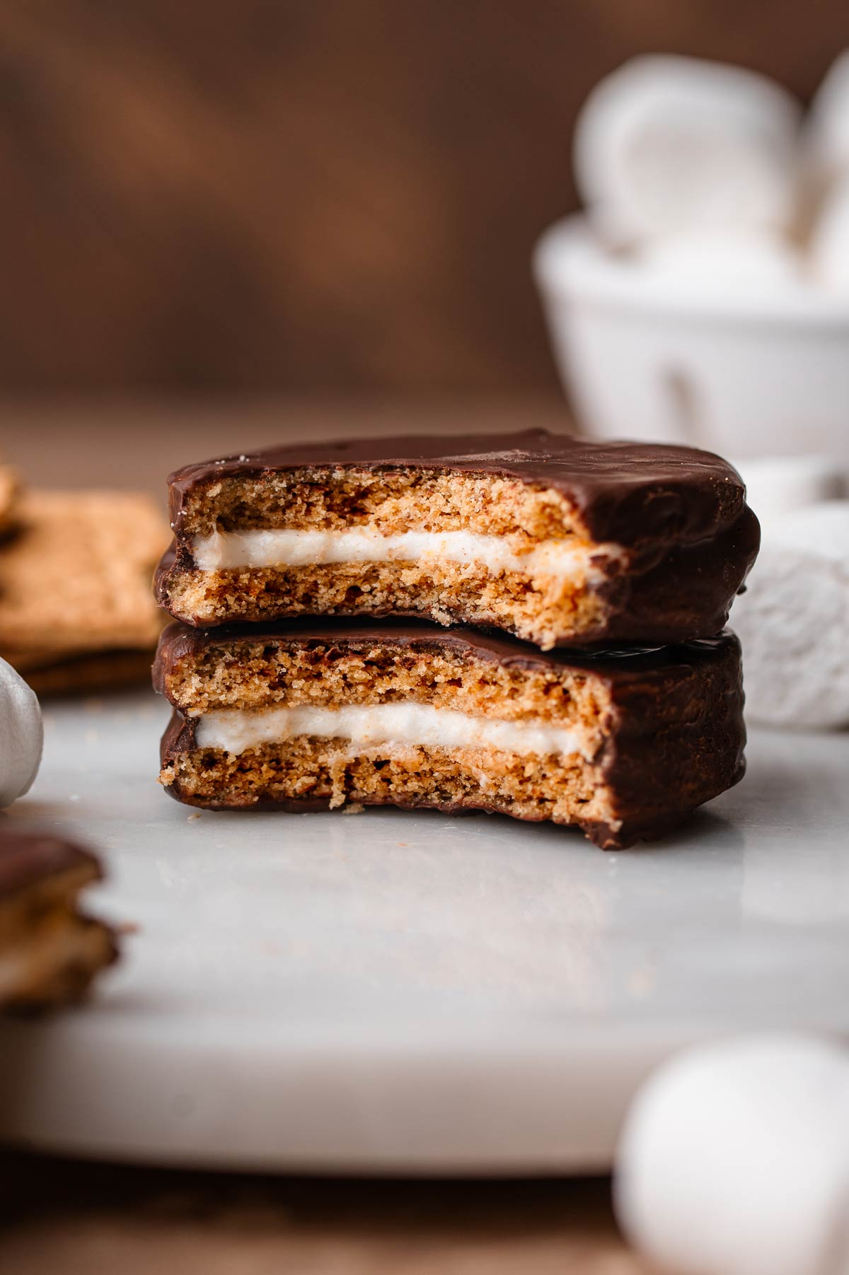 two homemade vegan moon pies stacked on each other with a bite taken out of them exposing the marshmallow center.
