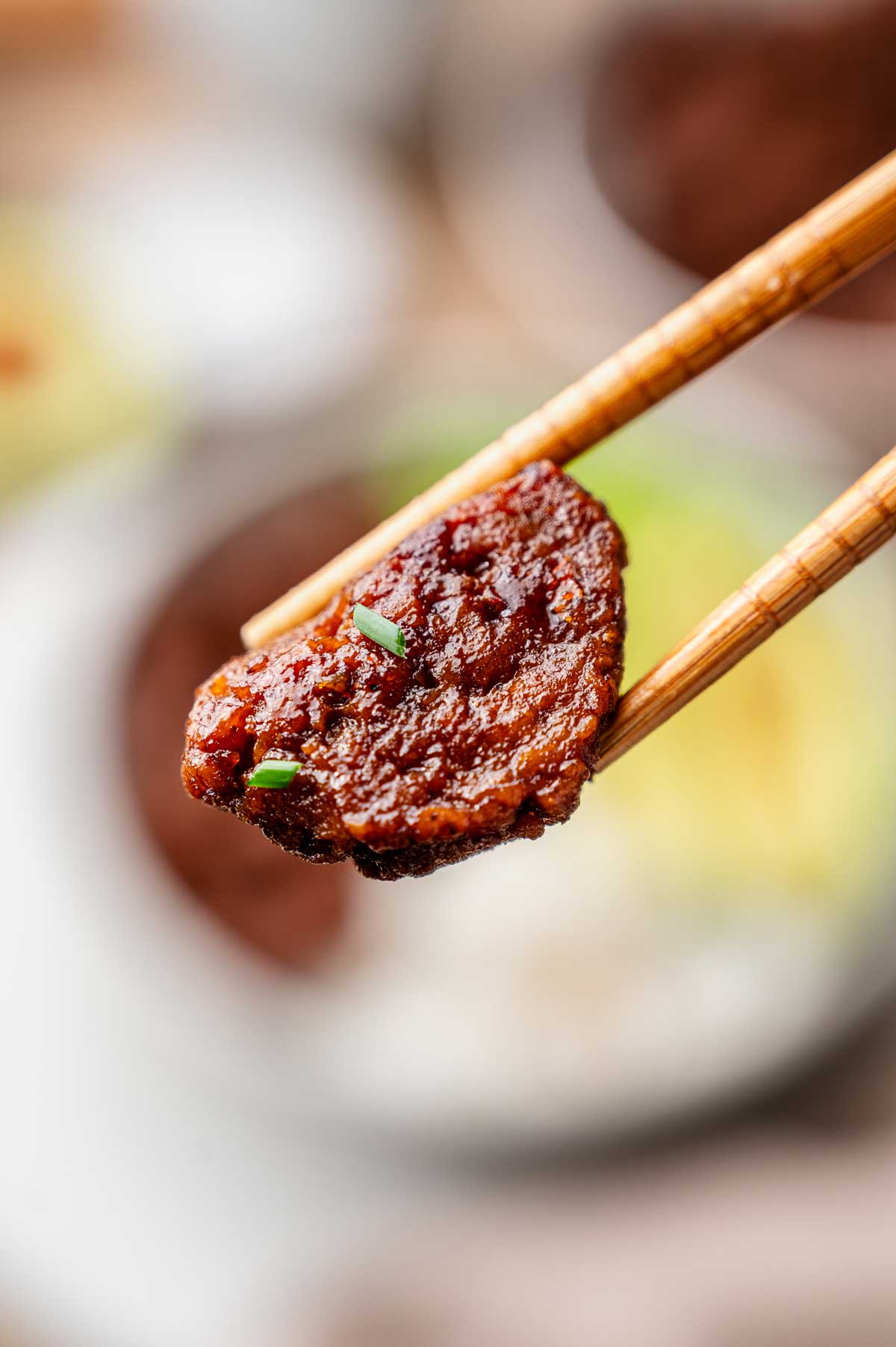 a piece of vegan beef being held with wooden chopsticks.