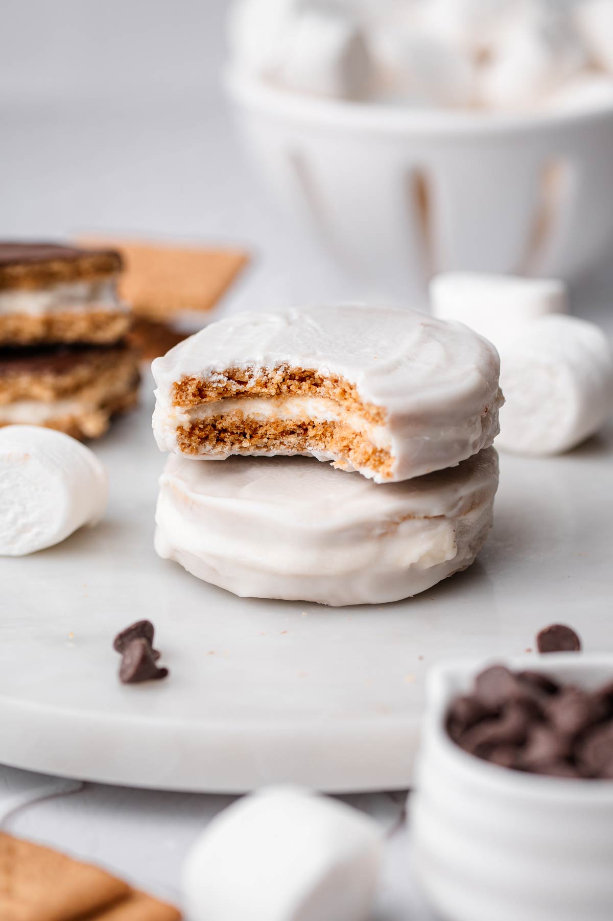 two white chocolate vanilla vegan moon pies stacked on each other with one with a bite taken out.