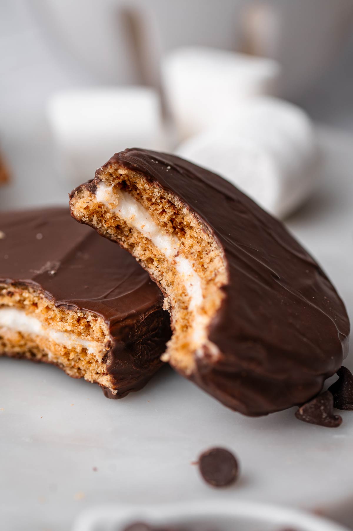 a half eaten vegan moon pie resting on the edge of another moon pie.