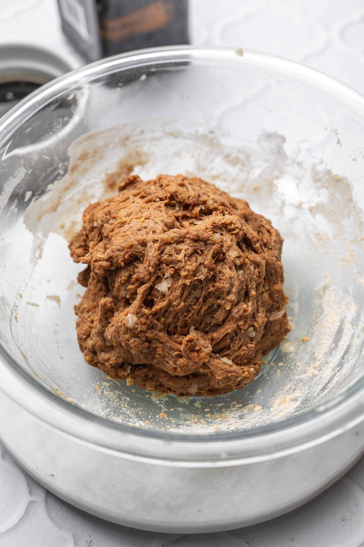 the seitan dough ball after kneading in a large glass bowl.