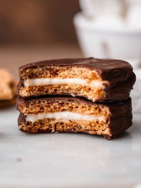 two homemade vegan moon pies stacked on each other with a bite taken out of them exposing the marshmallow center.