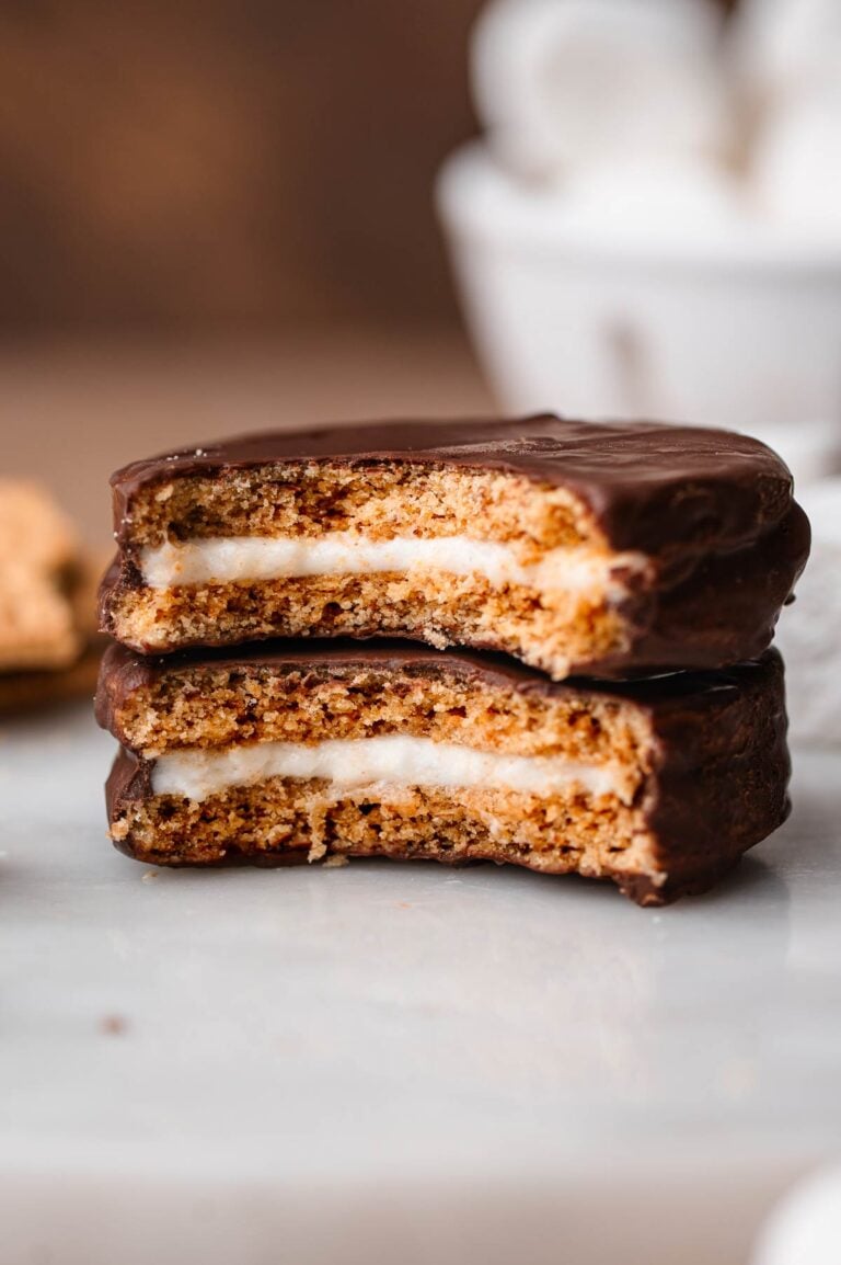two homemade vegan moon pies stacked on each other with a bite taken out of them exposing the marshmallow center.