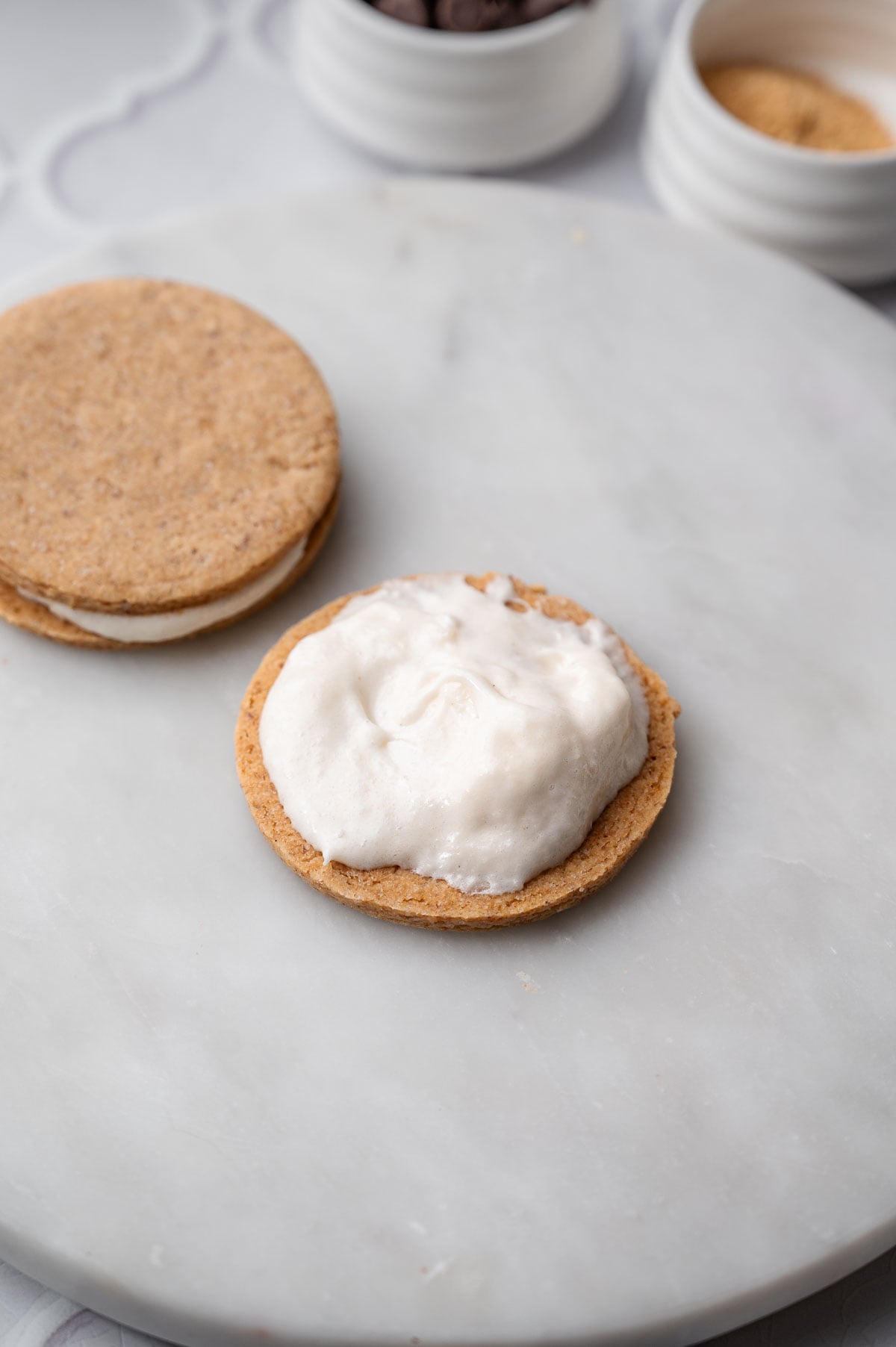 a baked vegan graham cracker cookie with marshmallow fluff scooped on top.