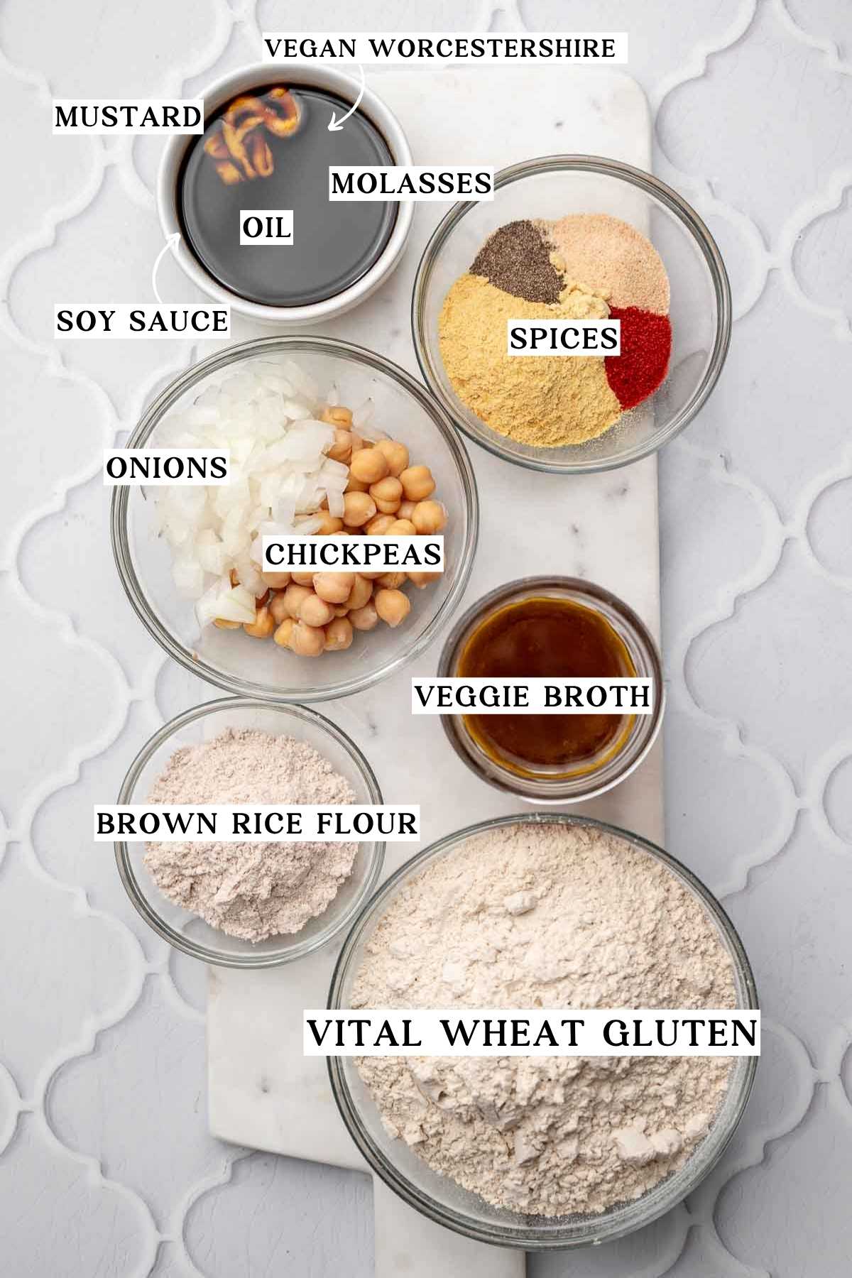 ingredients like vital wheat gluten, spices, chickpeas, and onions on a marble cutting board.