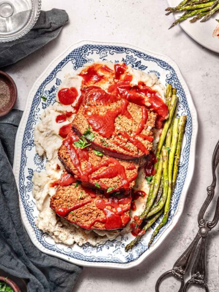three slices of vegan meatloaf made with Beyond Meat on a bed of mashed potatoes.