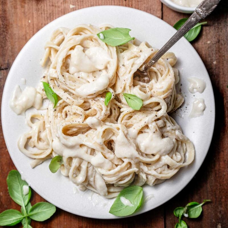 the best vegan alfredo without cashews on a plate with basil.