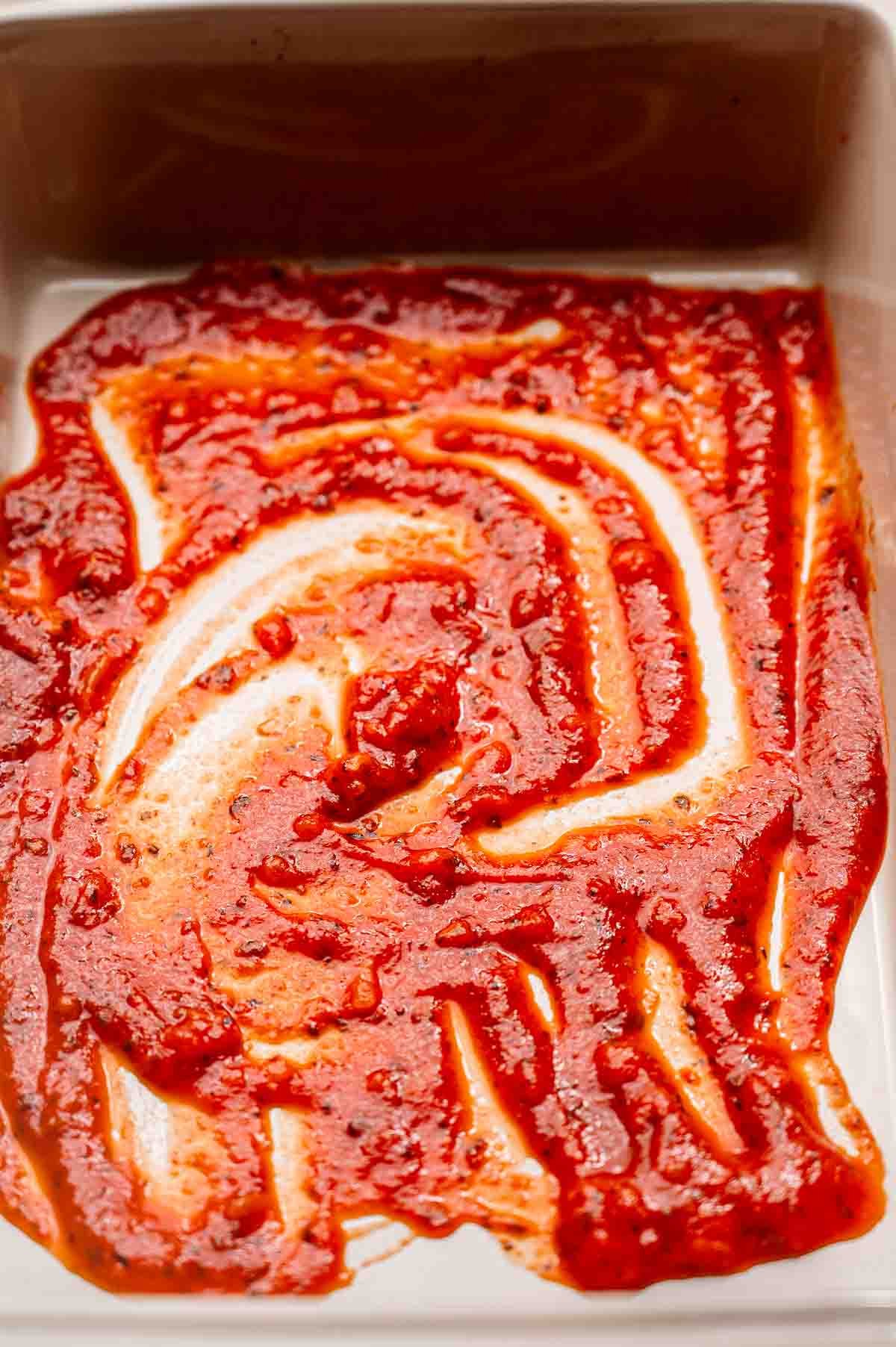 a baking dish with marinara sauce.