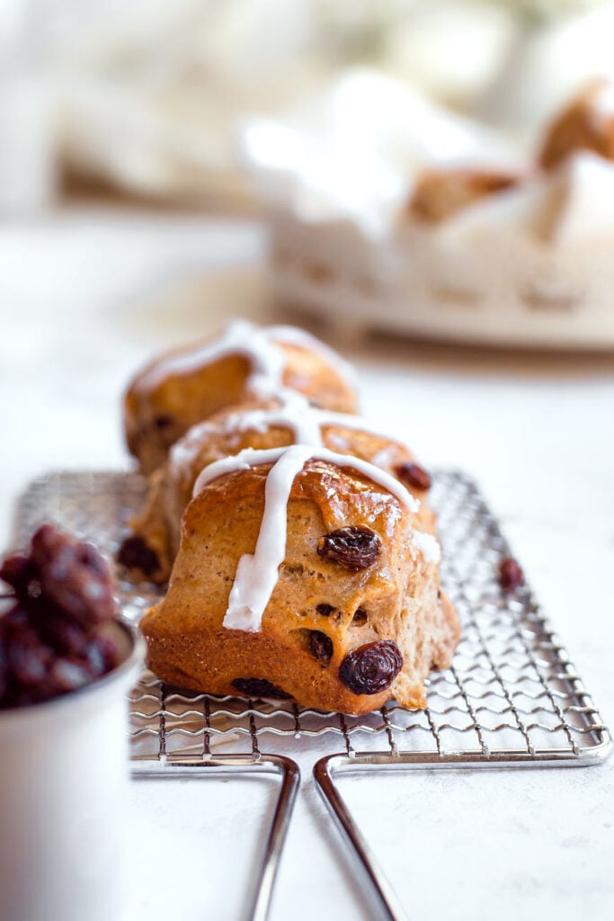 vegan hot cross bun with icing on cooling rack