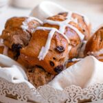 vegan hot cross buns with an icing cross in a basket.