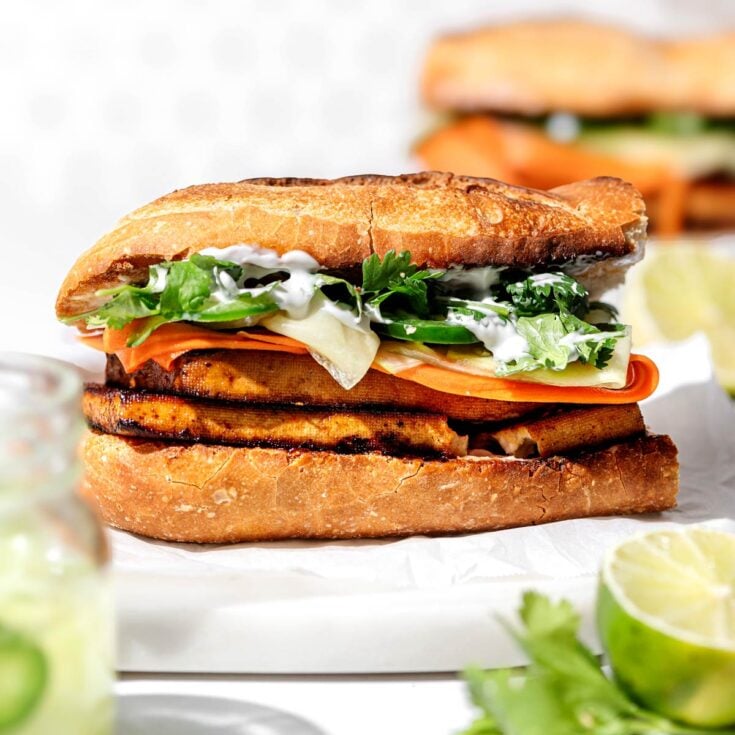 a vegan tofu banh mi sandwich on a white cutting board.