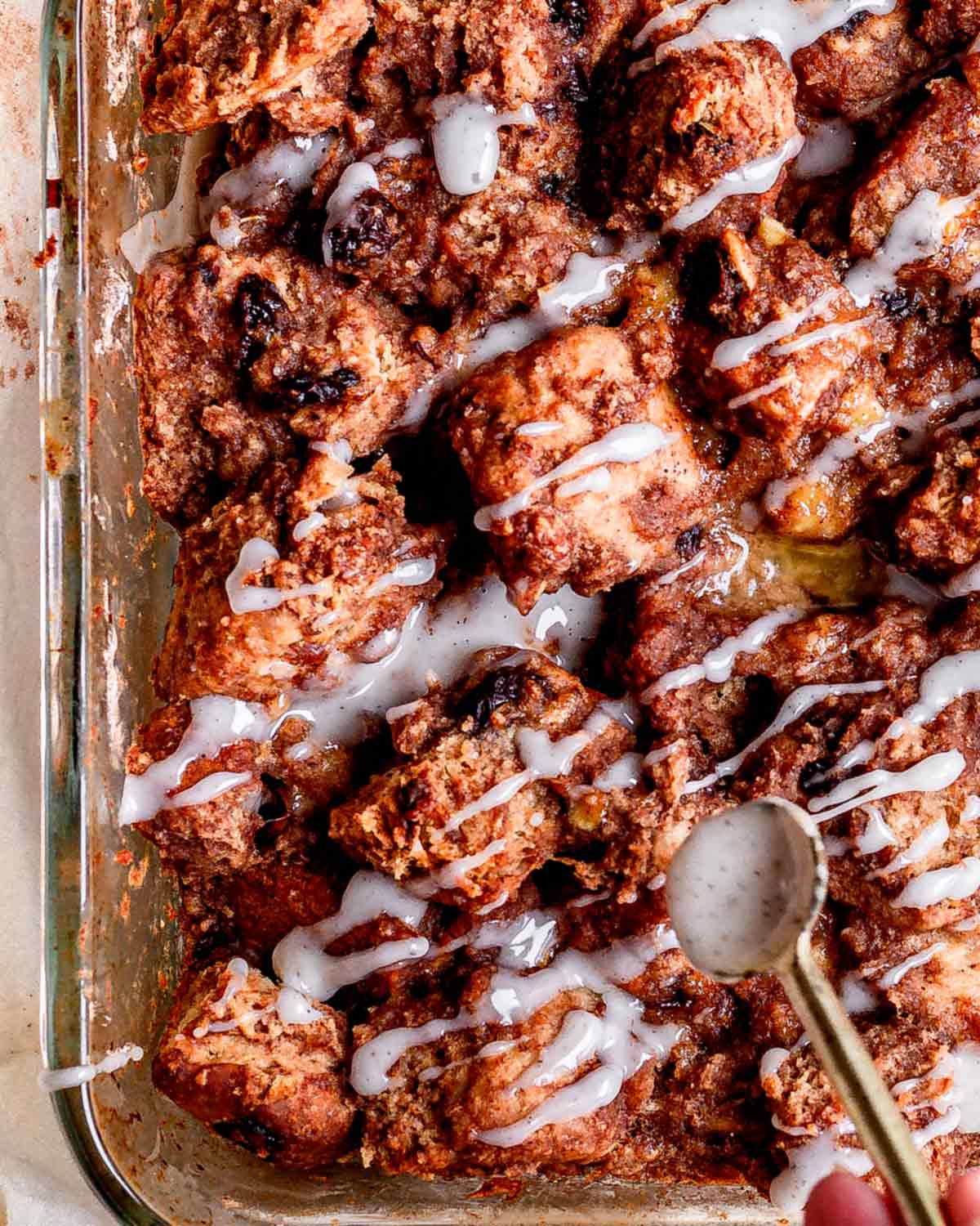 a hand drizzling icing over the baked french toast casserole.