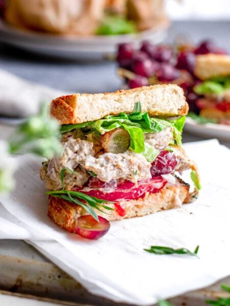vegan chicken salad inside a sourdough sandwich with tomato and butter lettuce.