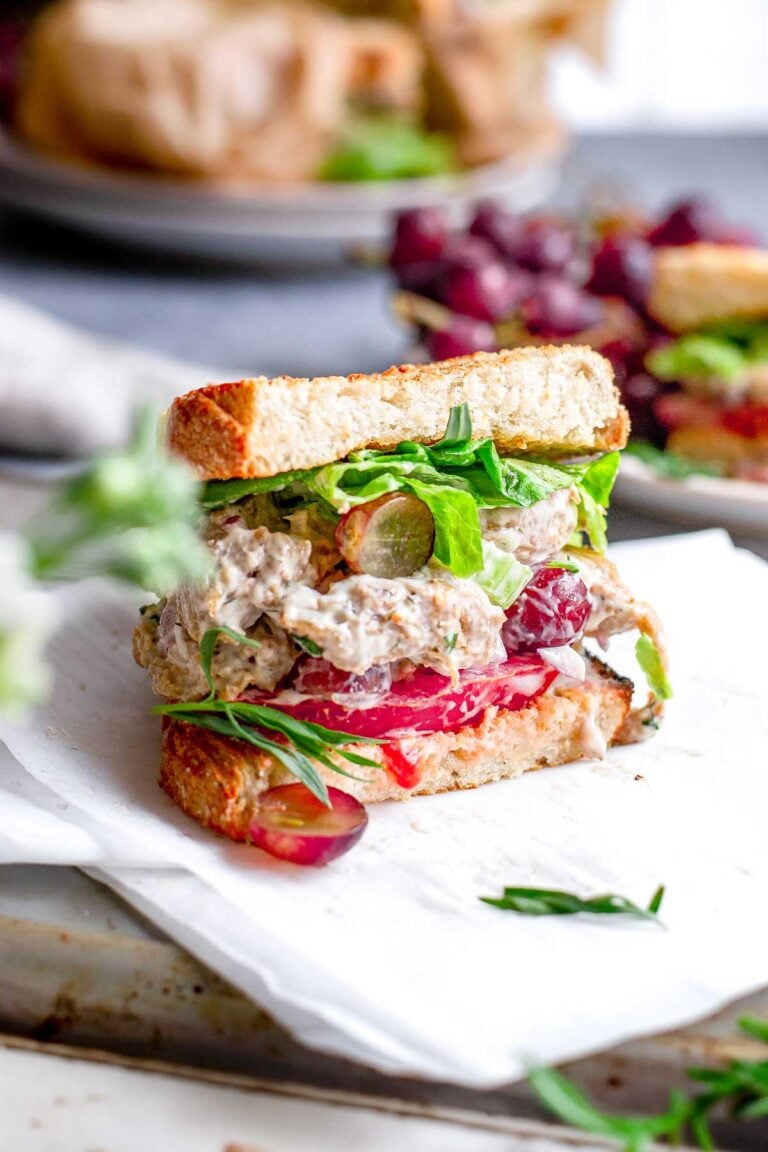 vegan chicken salad inside a sourdough sandwich with tomato and butter lettuce.