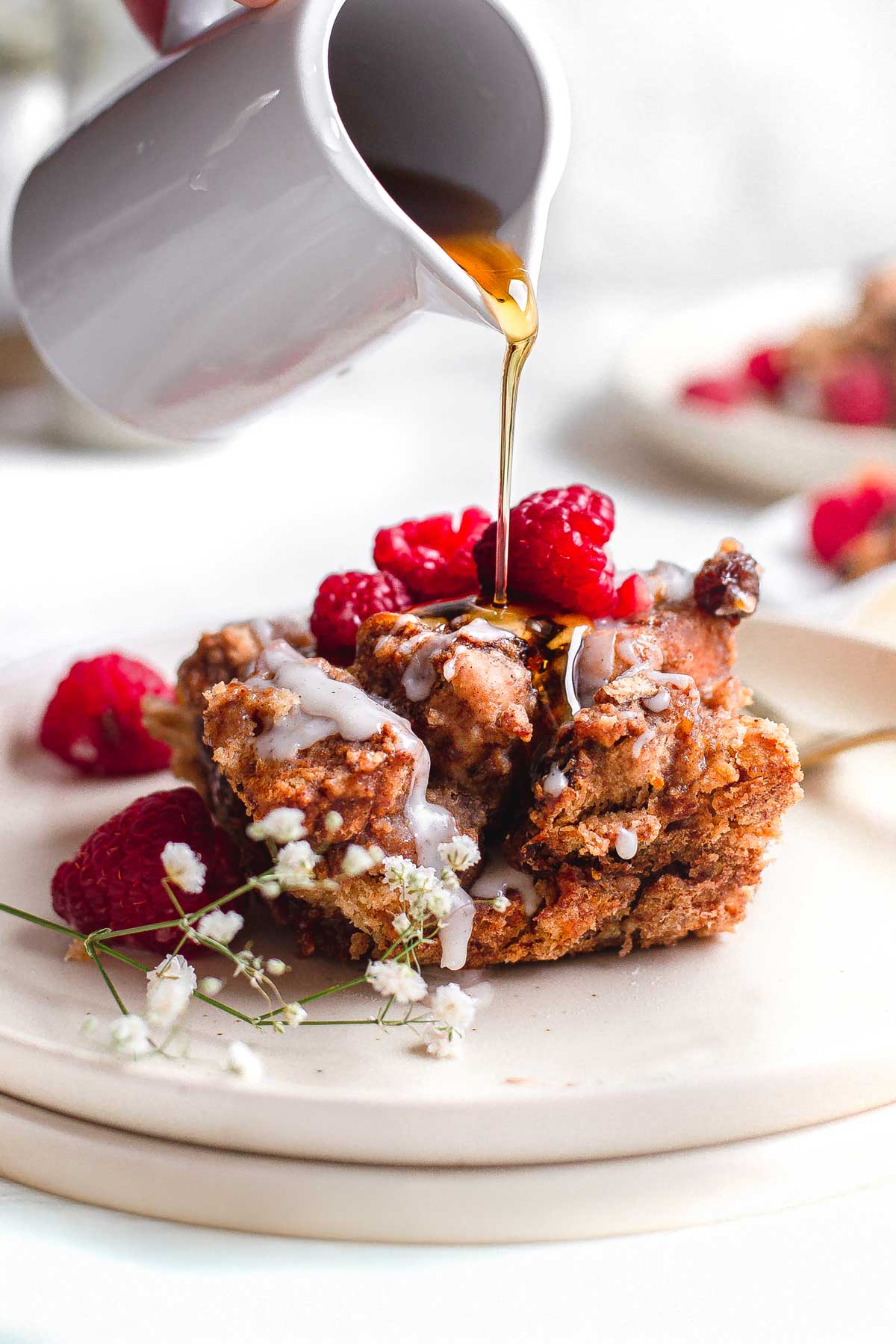 a slice of vegan french toast casserole with syrup being drizzled on top.