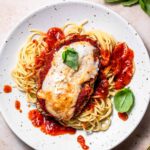 A plate of thin spaghetti topped with homemade vegan chicken parmesan.
