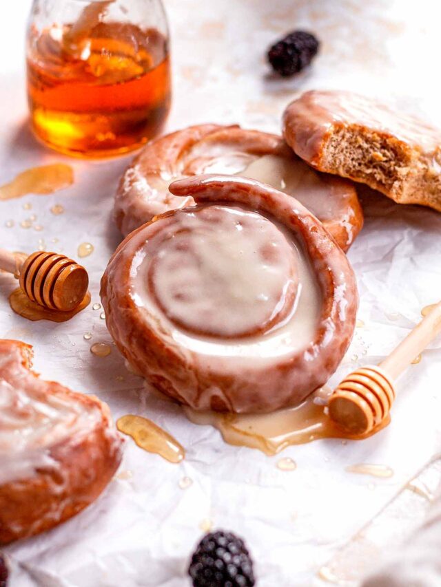 glazed homemade honey buns with a honey pot in the background.