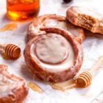 glazed homemade honey buns with a honey pot in the background.