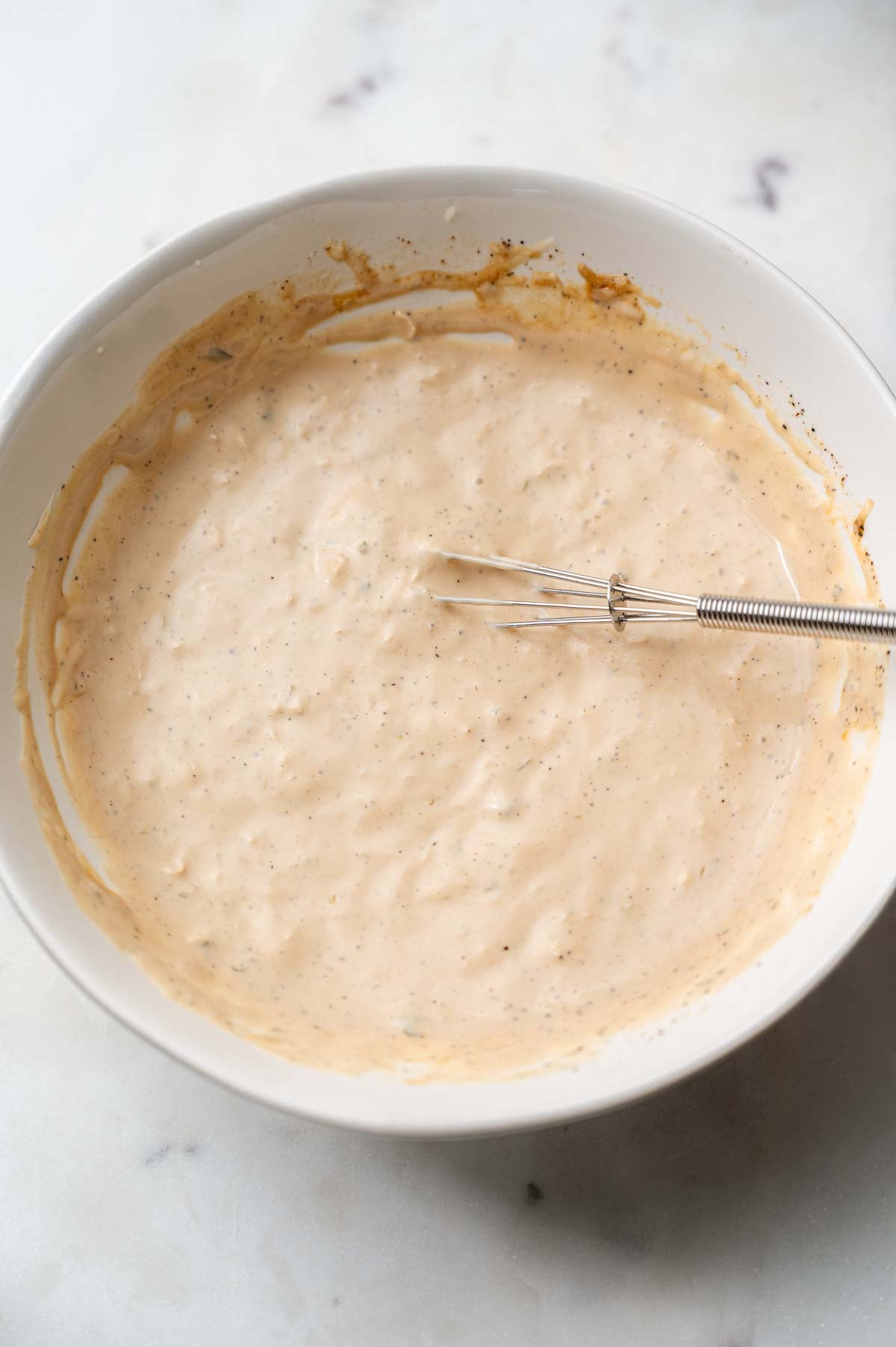 the mixed vegan caesar dressing in a white bowl.