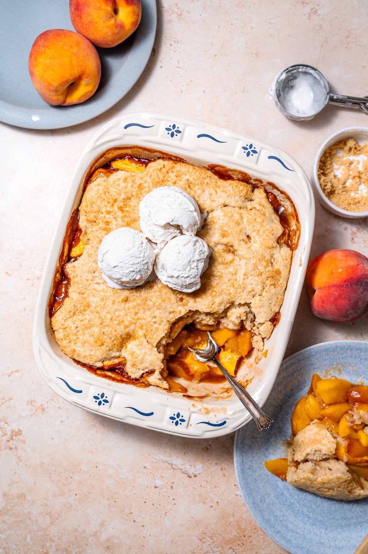 vegan peach cobbler with three scoops of vegan vanilla ice cream on top.