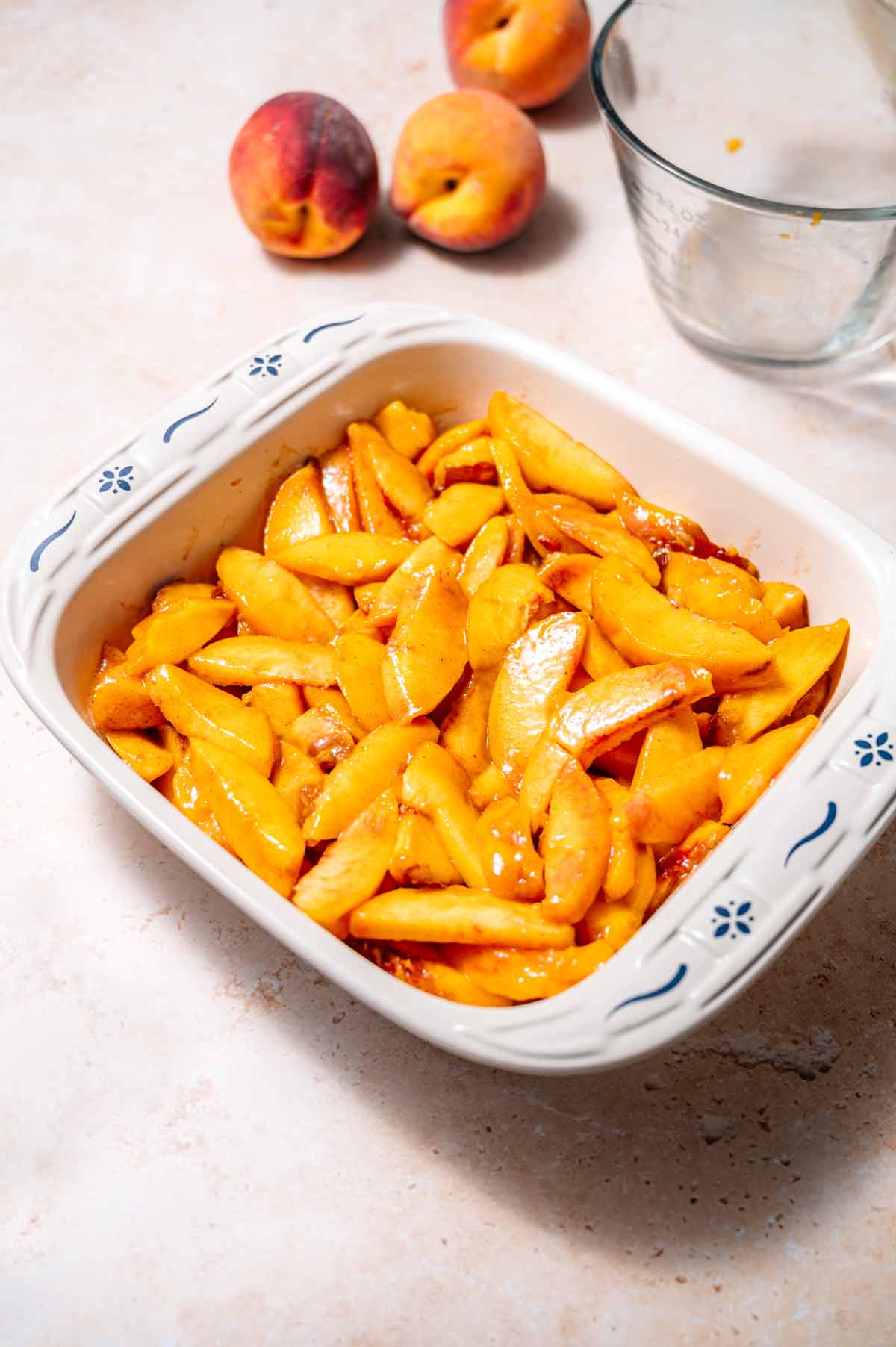 a square ceramic baking dish filled with the peach cobbler filling.