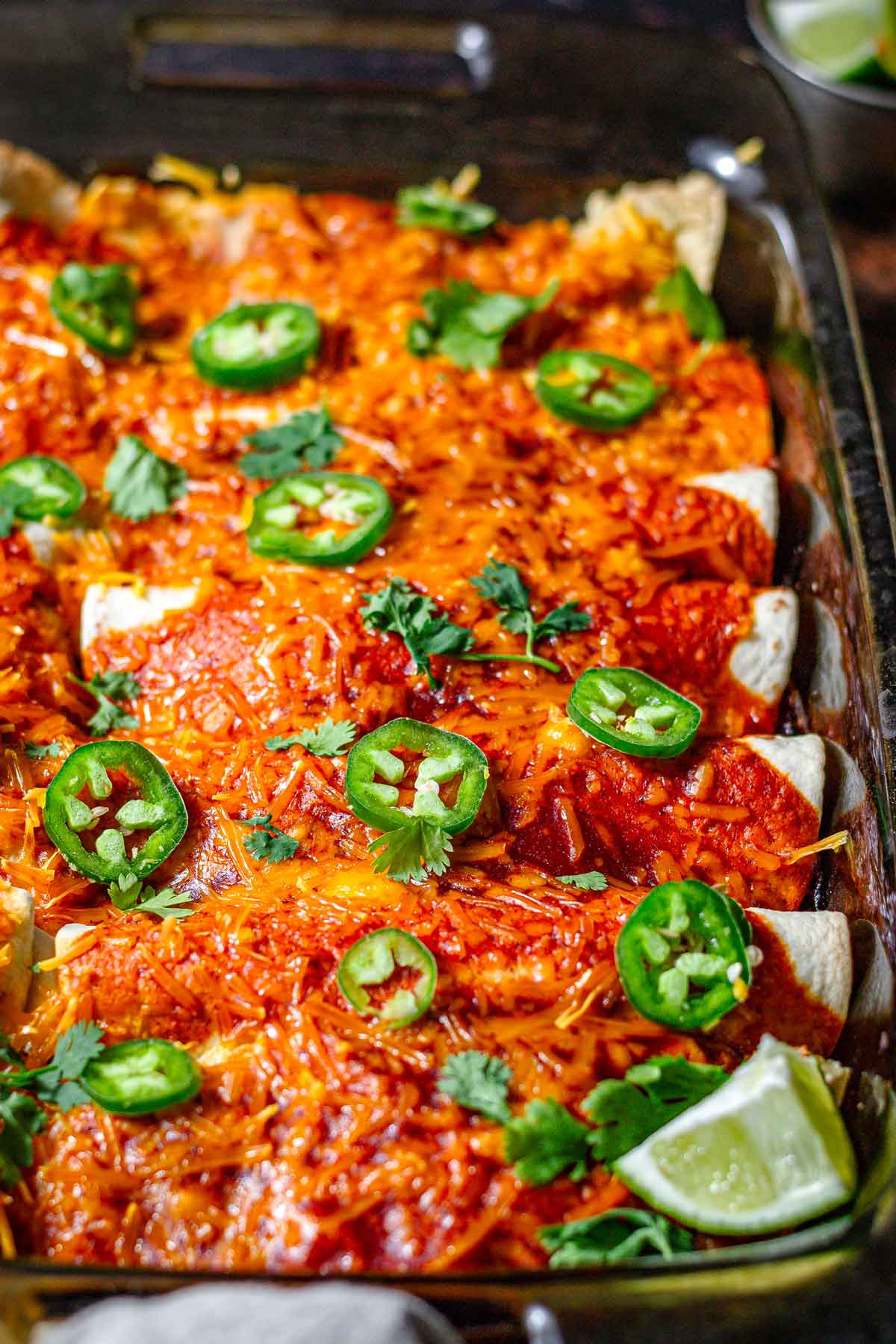 vegan enchiladas with cheese in a pan topped with jalapenos. 