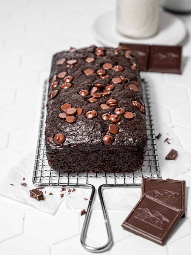 a loaf of vegan chocolate zucchini bread on a wire cooling rack.