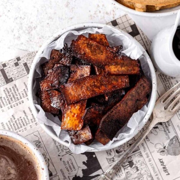 a bowl of tofu bacon on newspaper.