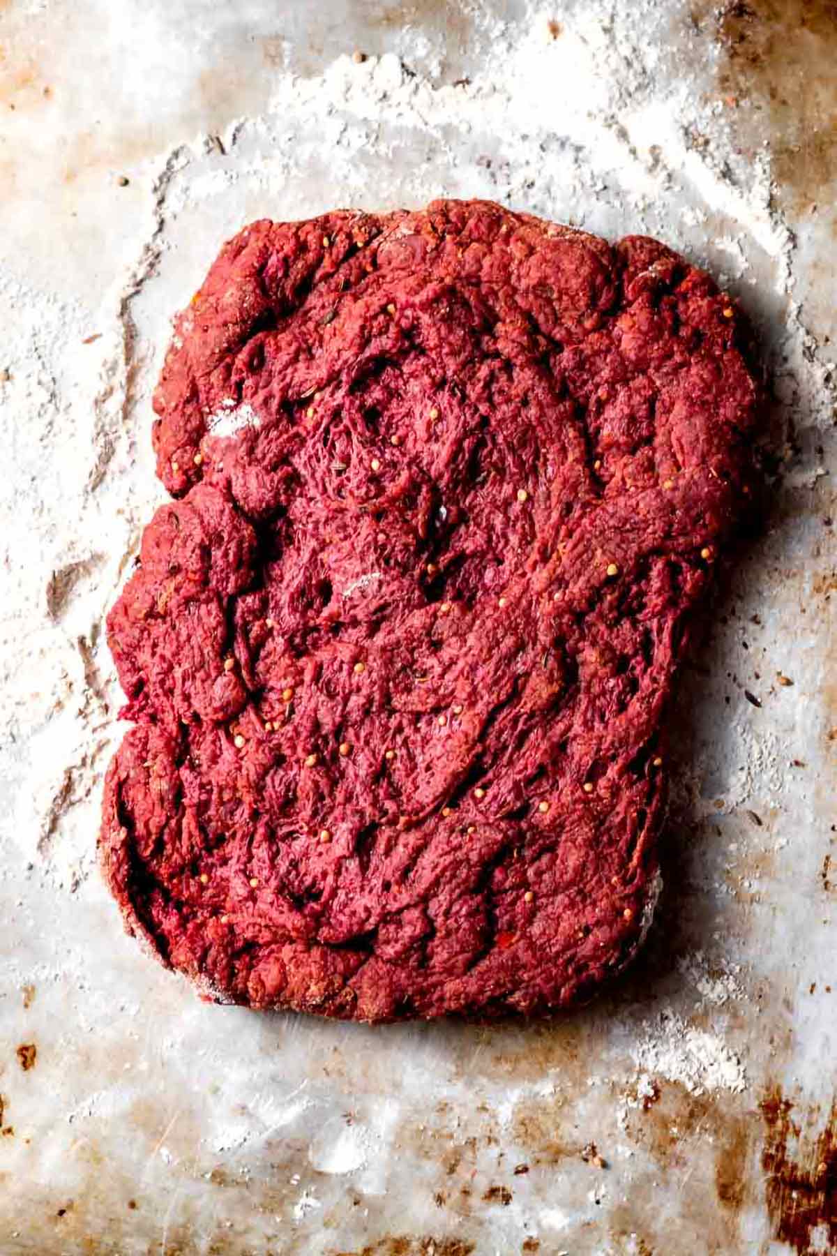 the seitan dough rolled out on a baking sheet.