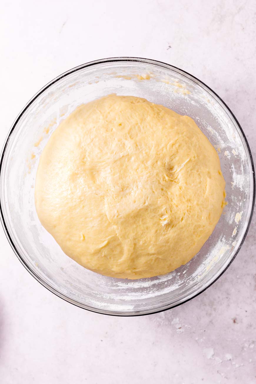 the risen vegan brioche dough in a glass bowl.