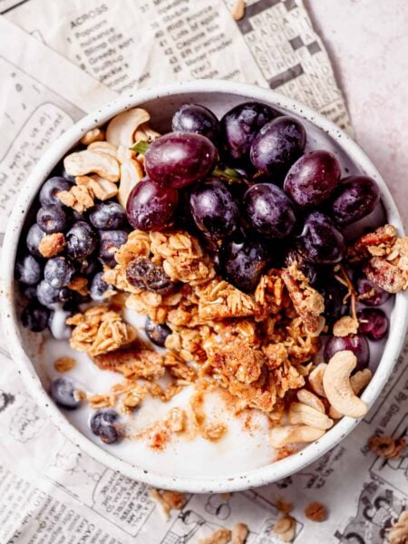 a bowl filled with dairy-free yogurt, air fryer granola and red grapes.