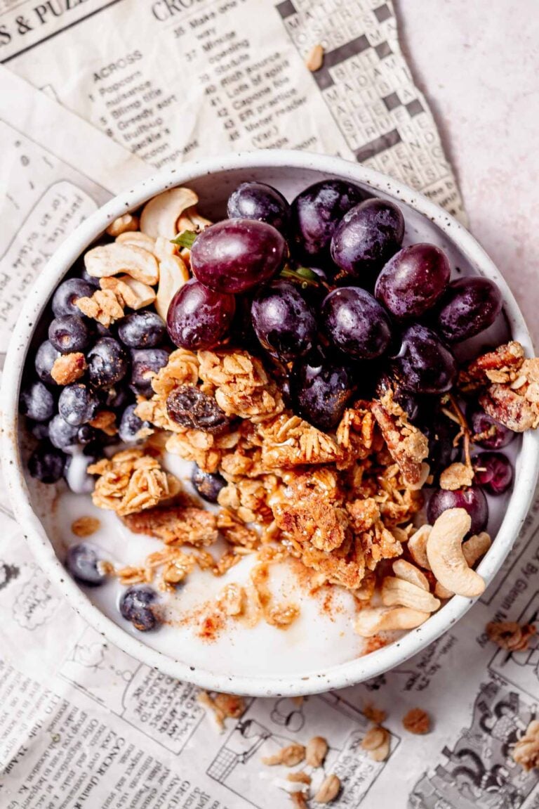 a bowl filled with dairy-free yogurt, air fryer granola and red grapes.