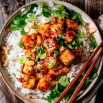 panfried sticky and crispy sesame tofu on a bed of rice.