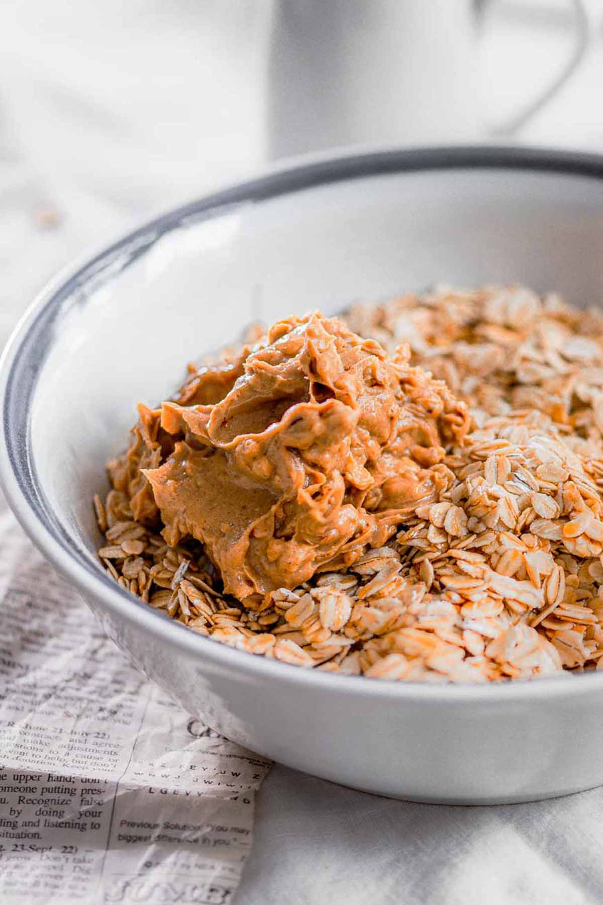 a white ceramic bowl with old fashioned oats and a scoop of peanut butter on top.