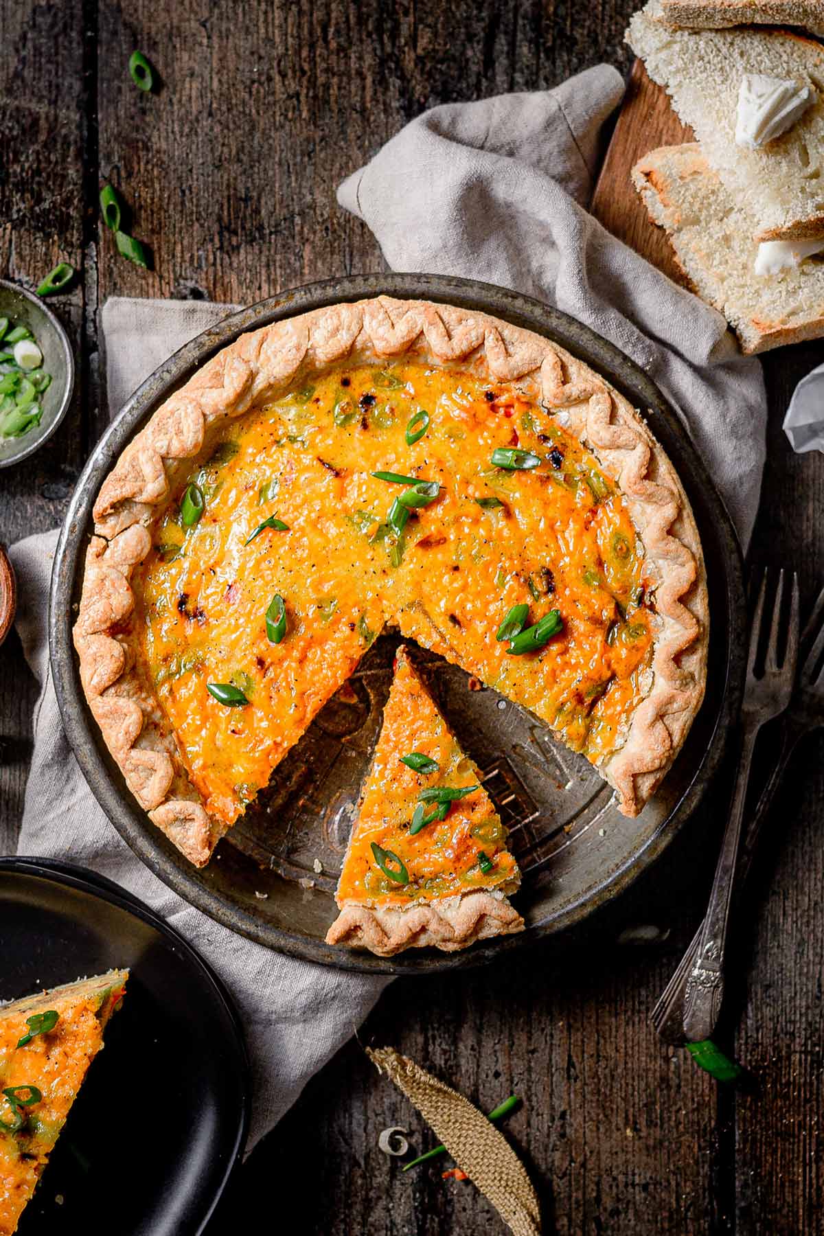 Overhead shot of sliced vegan Just Egg quiche in a pie pan, garnished with chopped green onions and ready to serve.