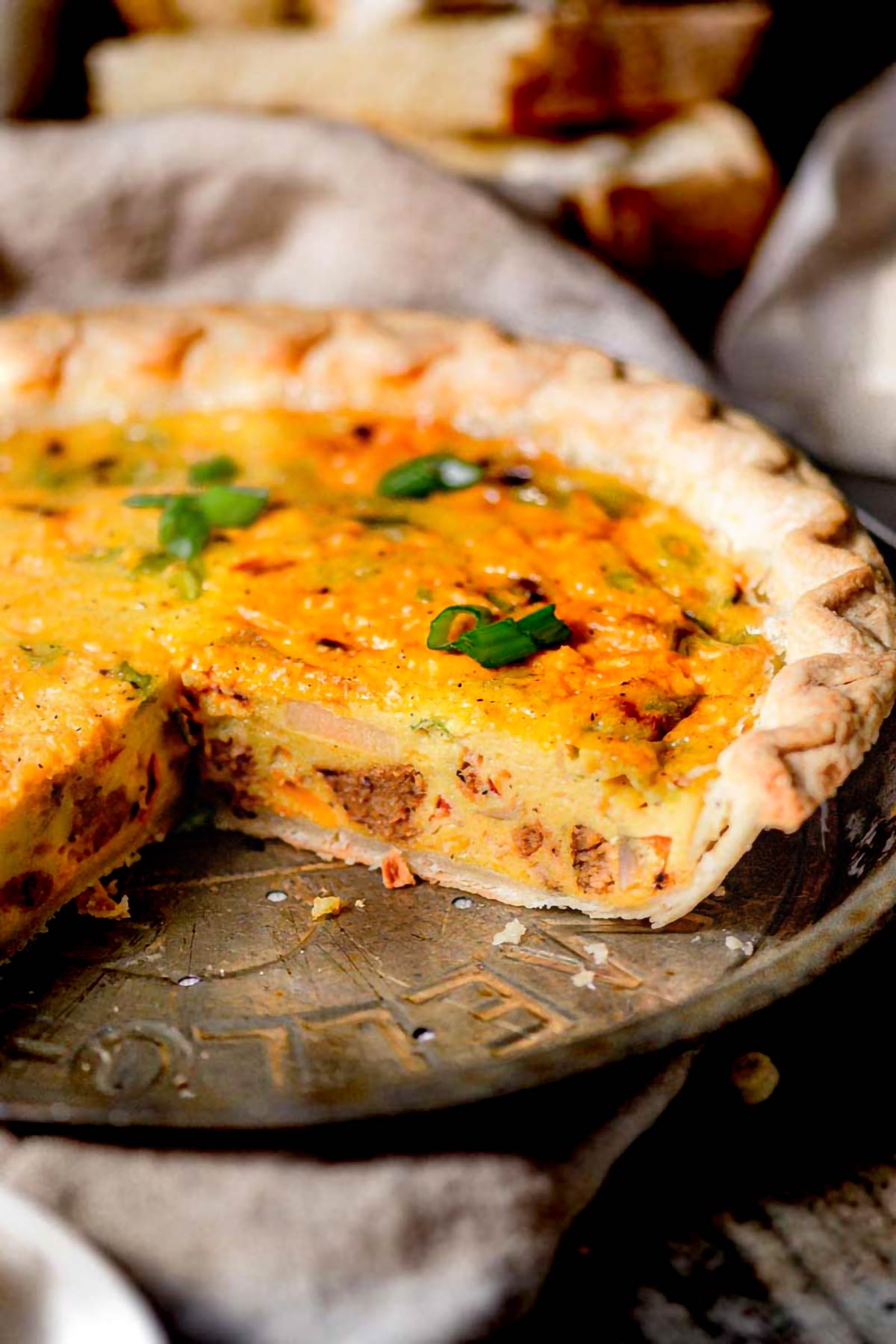 Close-up of vegan Just Egg quiche with plant-based sausage and red bell peppers baked into a flaky golden crust.
