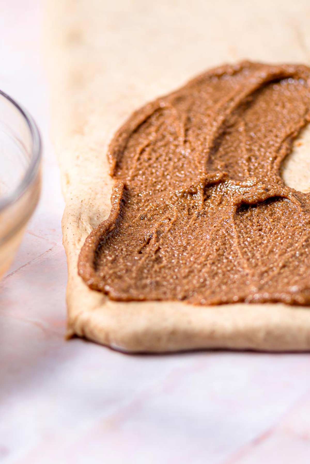 the vegan cinnamon roll dough rolled out with the biscoff filling spread on top.