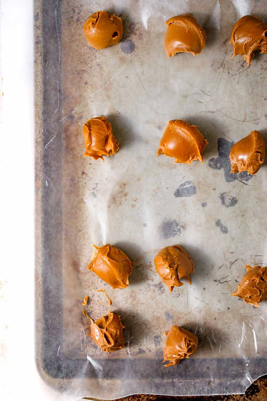 dollops of biscoff cookie butter on a lined baking sheet.