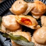 a vegan butternut squash ravioli cut in half exposing the creamy filling.