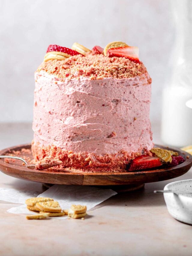 strawberry crunch cake on a wooden cake stand.