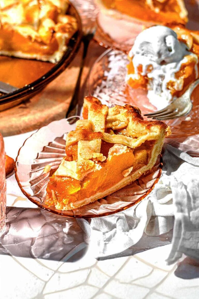 a sliced of peach pie made from canned peaches with a lattice crust on a glass pie plate.
