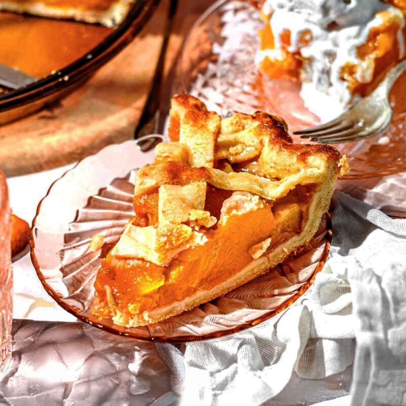 a sliced of peach pie made from canned peaches with a lattice crust on a glass pie plate.