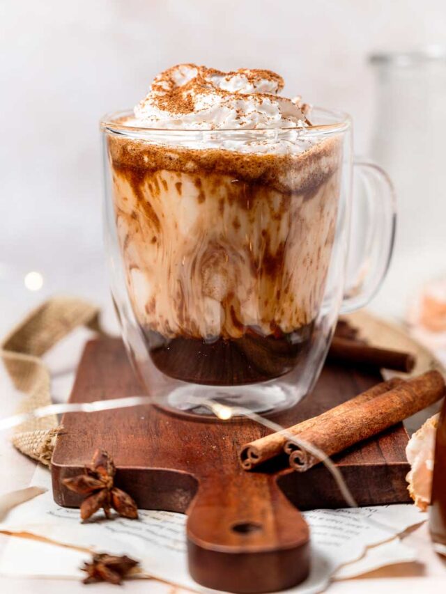 vegan iced pumpkin spice latte with oat milk in a glass on a cutting board.