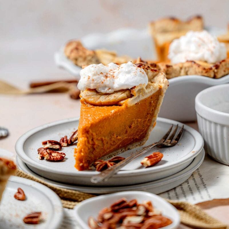 vegan and eggless pumpkin pie on a stack of grey plates.