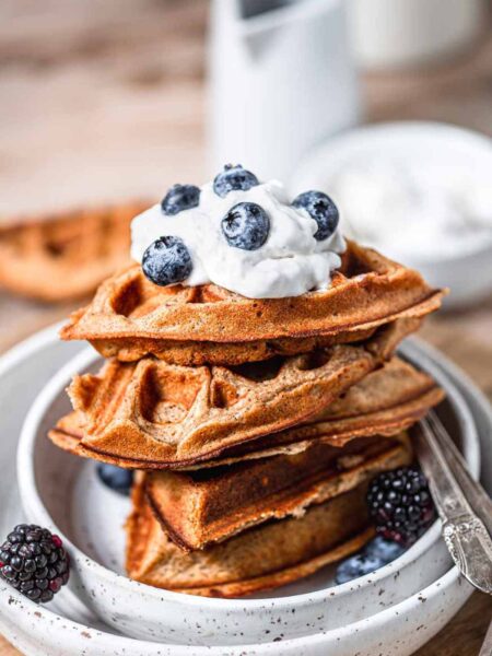 a stack of vegan protein waffles with dairy-free whipped cream and blueberries.