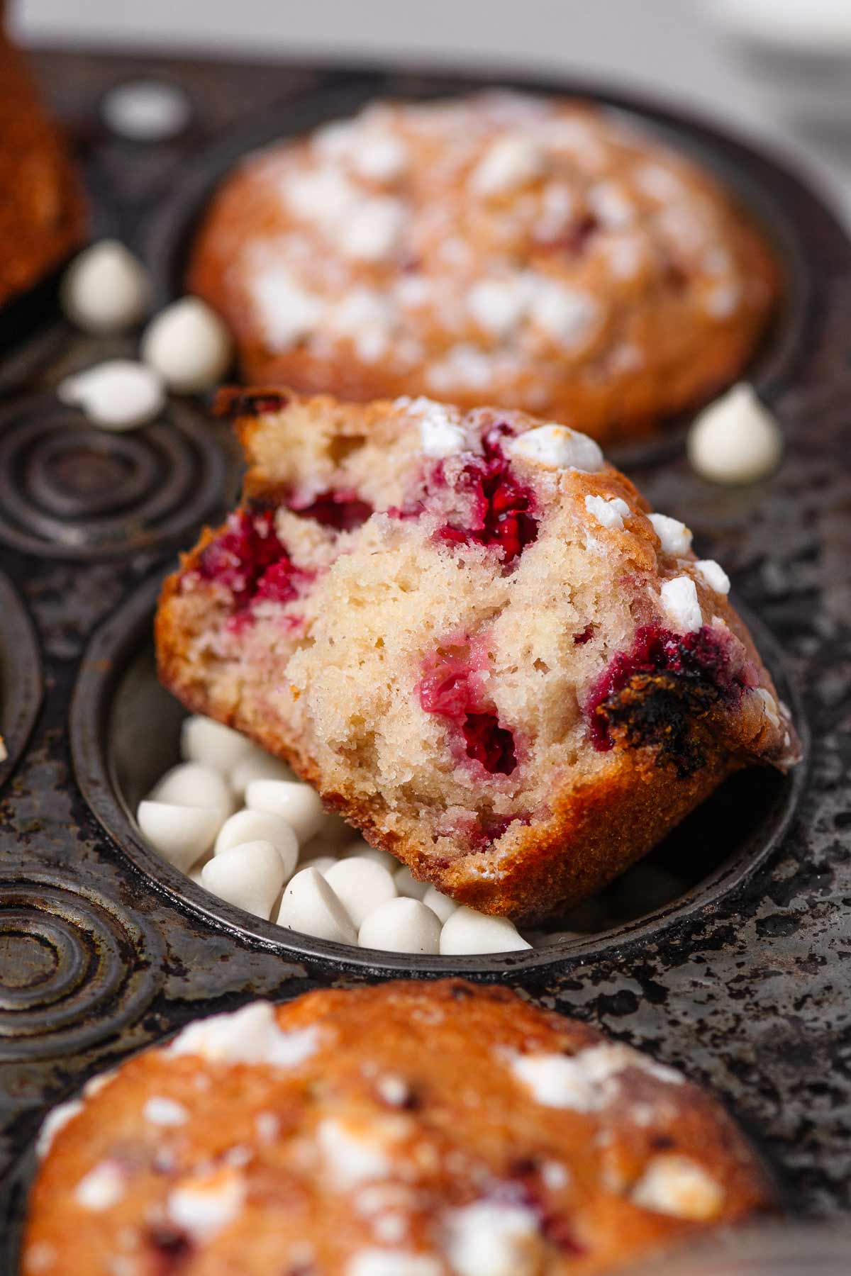 a vegan raspberry muffin with white chocolate in a muffin tin.